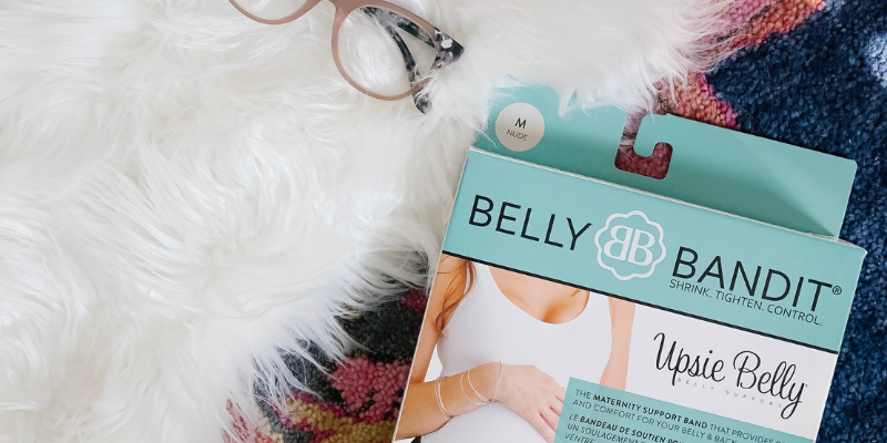 Belly Bandit Upsie Belly Maternity Support Band with glasses on rug