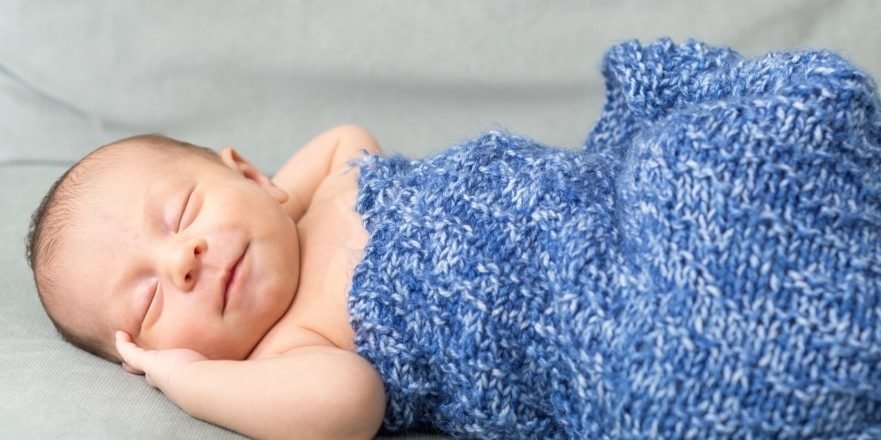 Baby sleeping in a blue knit sleep sack