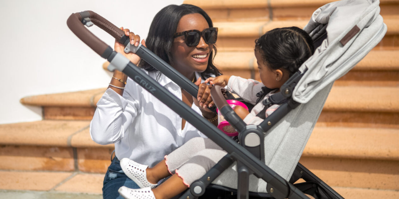Woman crouching beside stroller to talk to her baby
