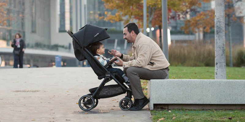Dad sitting and talking to child in Nuna TRVL LX travel stroller