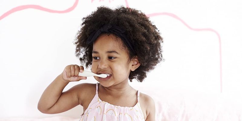 Toddler brushing their teeth with a Jack N' Jill training toothbrush
