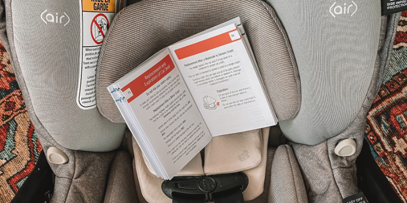 Car seat manual open to the car seat expire page sitting inside a Maxi-Cosi Infant Seat