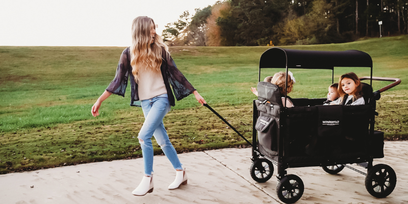 Woman Pulling WonderFold W4 Luxe Quad Stroller Wagon With Children Sitting Inside 