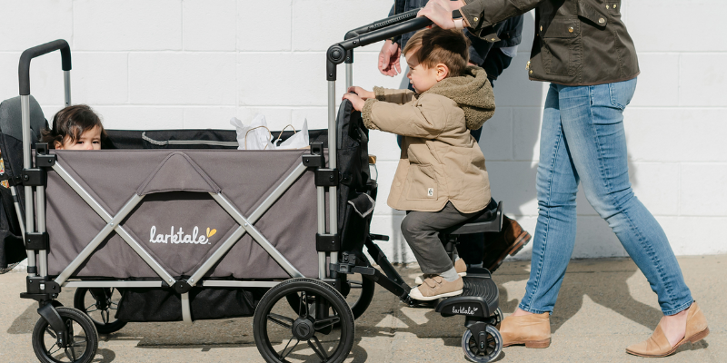 Larktale Caravan V3 2-Seater Stroller Wagon With Child Sitting Inside and Toddler and Woman Pushing