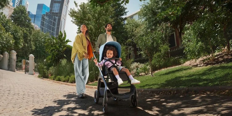 Parents pushing baby in stroller in a park