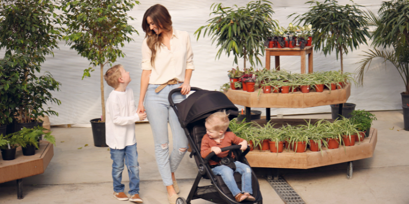 Baby Jogger City Tour 2 Stroller With Little Boy Sitting Inside and Woman and little boy Standing Behind it