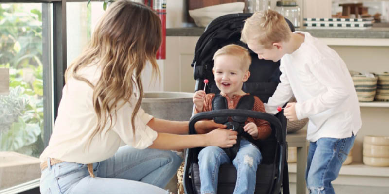 Baby Jogger City Tour 2 Stroller With Toddler Sitting Inside and Woman and Little Boy Looking at Him