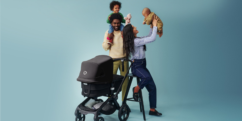 Man and Woman holding babies beside stroller