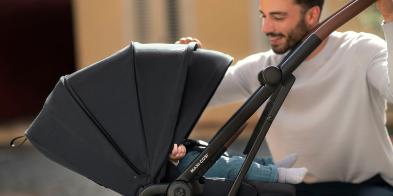 Dad sitting beside baby in a Maxi-Cosi Leona Ultra Compact Stroller