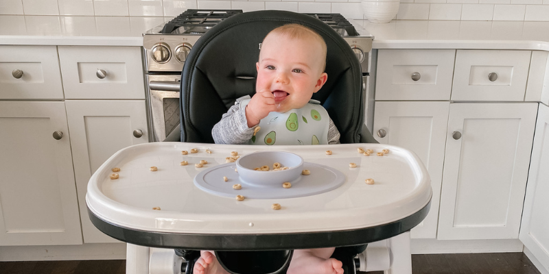 Baby eating cheerios, sitting in a Peg Perego Siesta High Chair