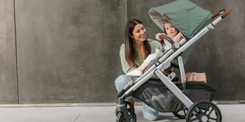 Woman Kneeling Beside Stroller With Toddler Sitting Inside