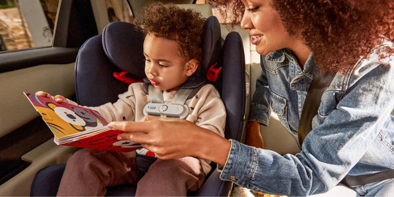 Woman Reading Child a Book While He Sits n the Cybex Eternis S SensorSafe All-In-One Convertible Car Seat