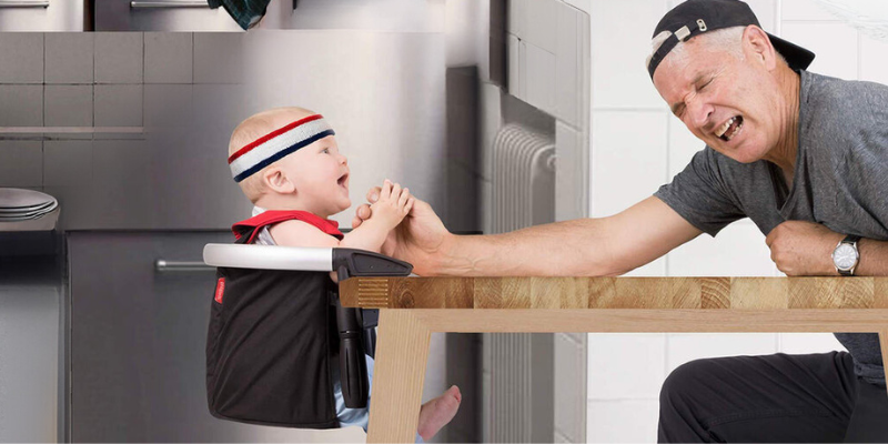 Phil & Teds Lobster Travel & Portable High Chair With Baby Sitting Inside Pretending to Arm Wrestle Man