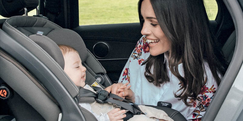 Woman In Back Seat With Newborn in Peg Perego Infant Seat