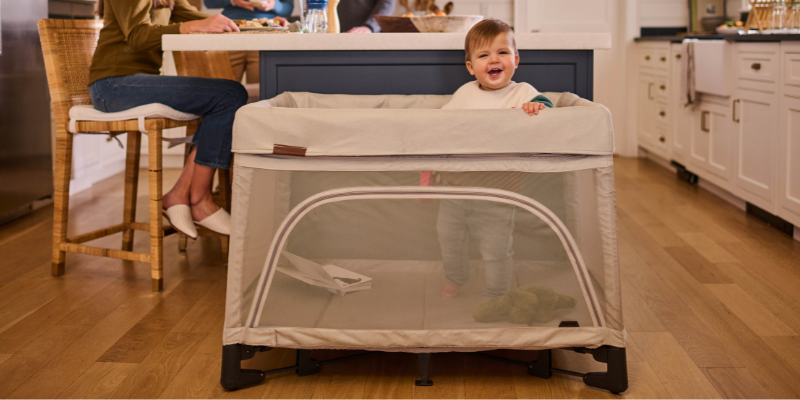 Baby standing in the UPPAbaby REMI Playard in CHARLIE