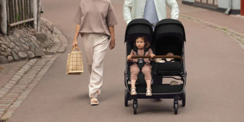 Dad pushing child in Nuna TRVL dubl Stroller