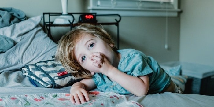 Little boy lying down on his parent's bed