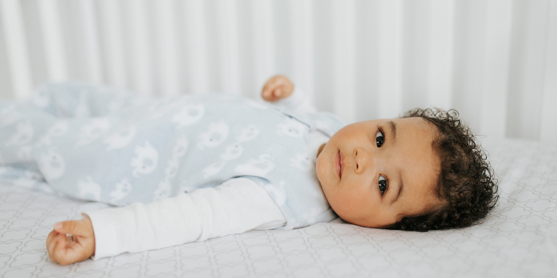 baby in crib wearing HALO blue and white fleece Sleep Sack