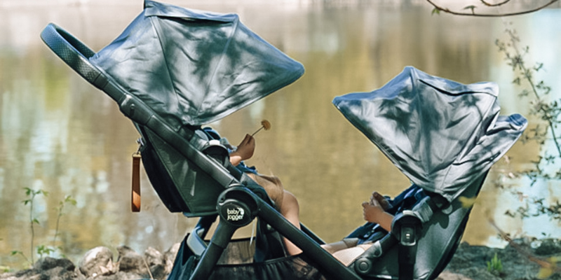 Two children sitting in the Baby Jogger City Select 2 Stroller by the waterfront