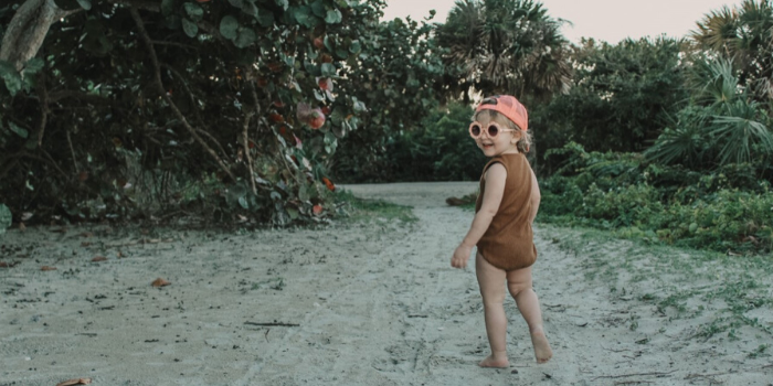 Kid Looking Back and Smiling With Sunglasses and Pink Hat on