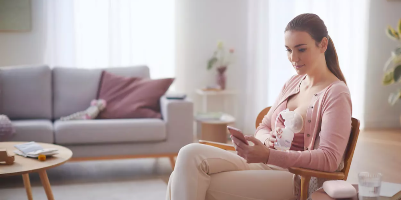Woman Sitting Down Looking at Her Phone and Pumping