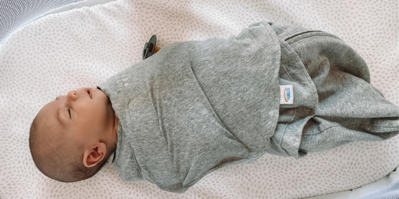 Baby swaddled up sleeping in a bassinet