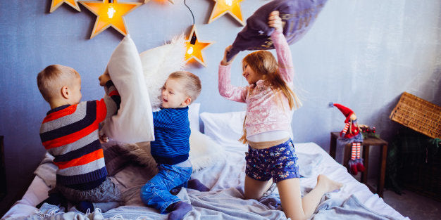 Three Kids Having a Pillow Fight on A Bed
