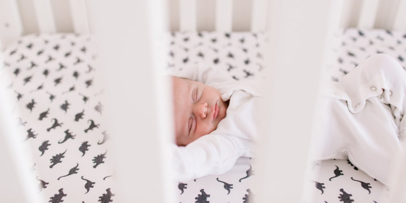 Newborn Stretching Their Arms While Sleeping in Crib