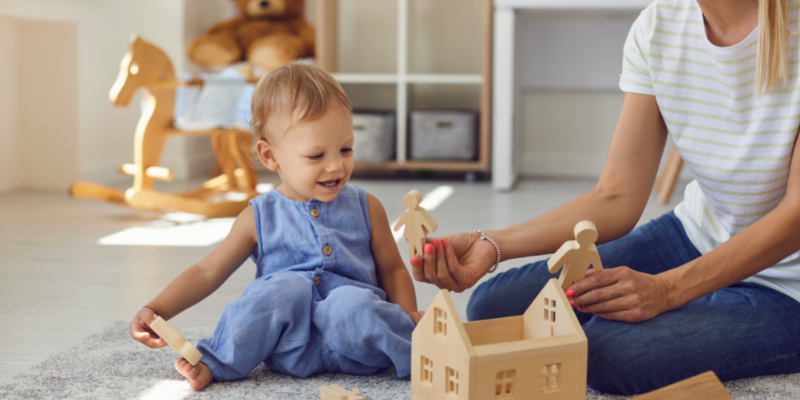 Woman Sitting With Toddler on Floor Playing With Wooden Toys