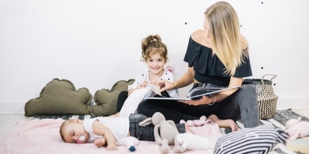 Mom sitting on a rug with her children reading a picture book