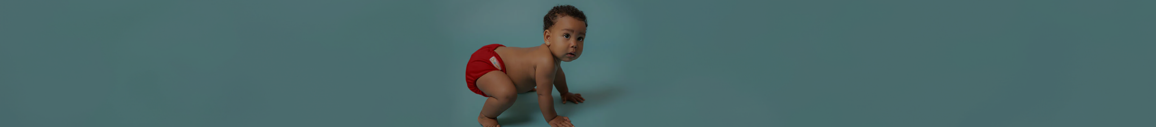 Baby squatting wearing a red Lil Helper cloth diaper