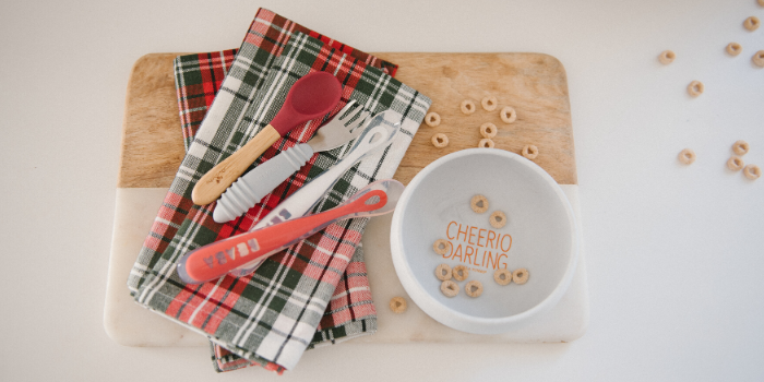 Baby Utensils on Plaid Napkin With Bowl of Cereal Beside It on Table