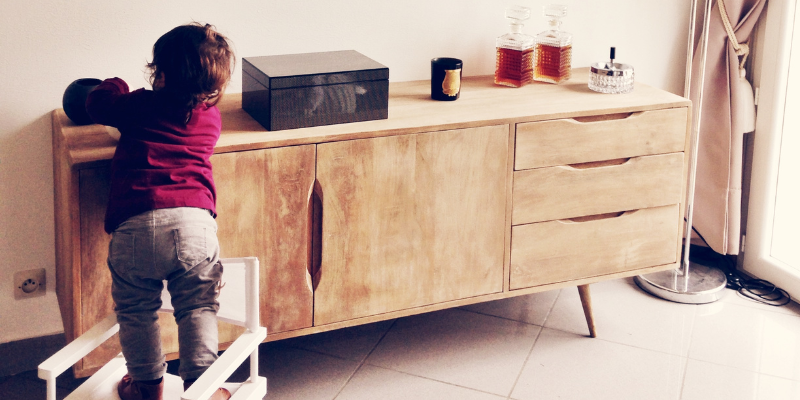 Toddler standing on chair reaching for a cabinet