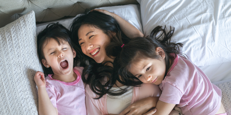 Mother and two daughters cuddling and laughing in bed