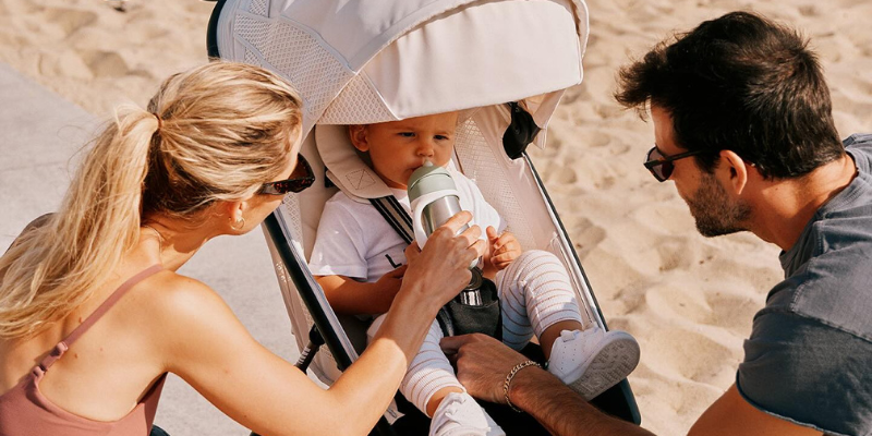 Mom and dad on beach with baby in Cybex Avi Spin Stroller