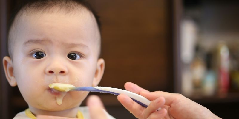 Baby with dripping spoon in his mouth