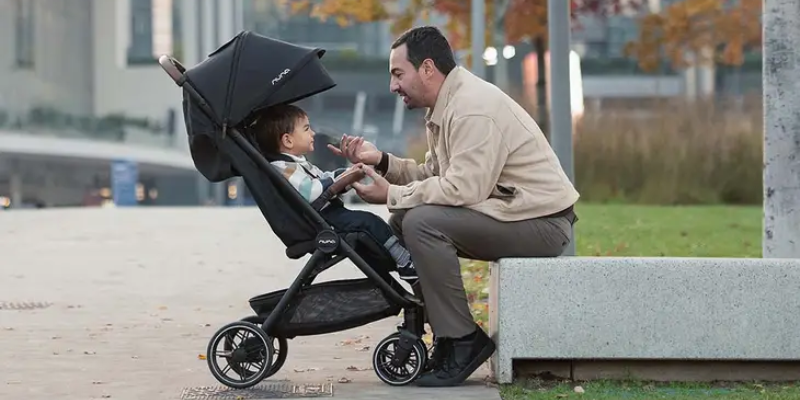 Baby sitting in Nuna TRVL LX stroller with father sitting facing them