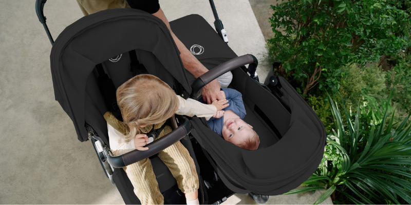 Baby and toddler sitting in Bugaboo Donkey 5 stroller with one seat parent-facing and one seat world-facing