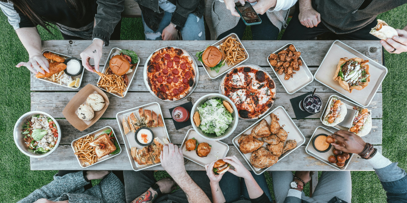 family gathered around a picnic table with a spread of food on top