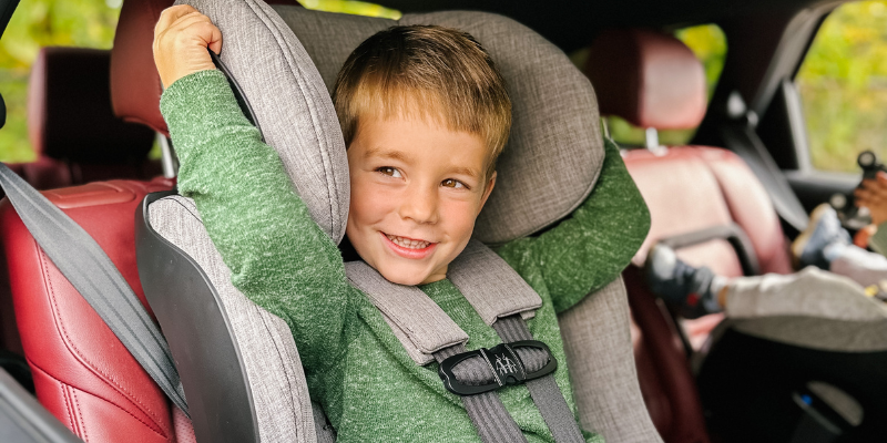 Little boy in green sweater sitting in Clek Foonf Convertible car seat
