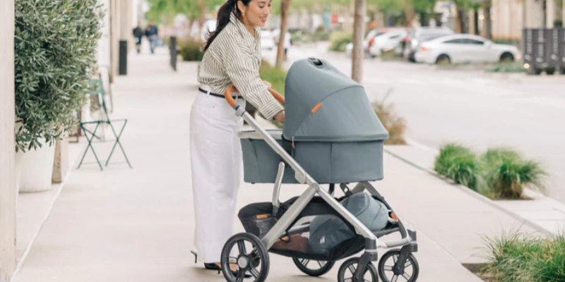 Mom pushing UPPAbaby Vista v3 on sidewalk with bassinet attached 