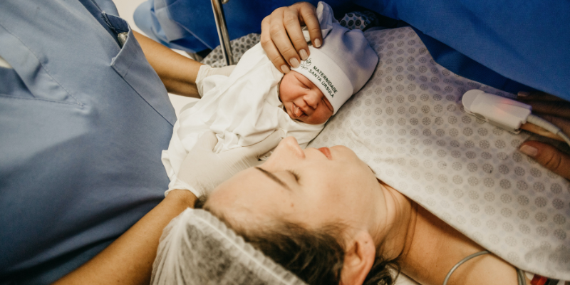 A woman holding her new, clothed baby, after a cesarean