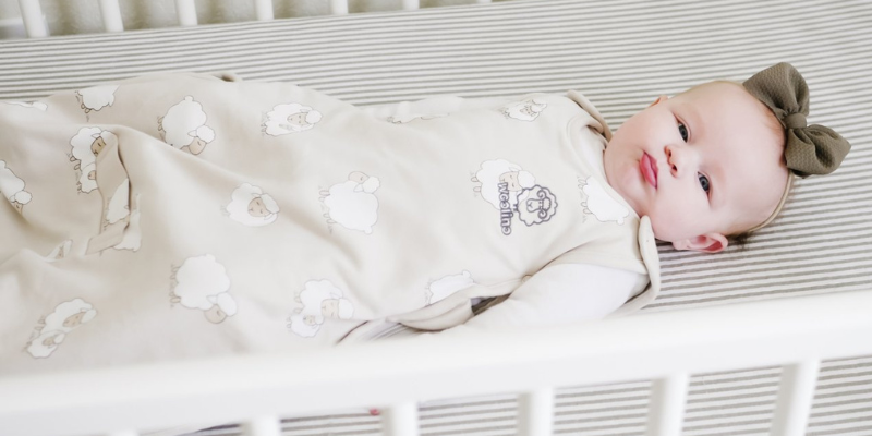 Baby laying in a crib wearing a Woolino Sleep Sack