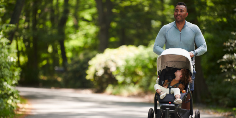 Man Pushing Jogging Stroller With Baby Sitting Inside