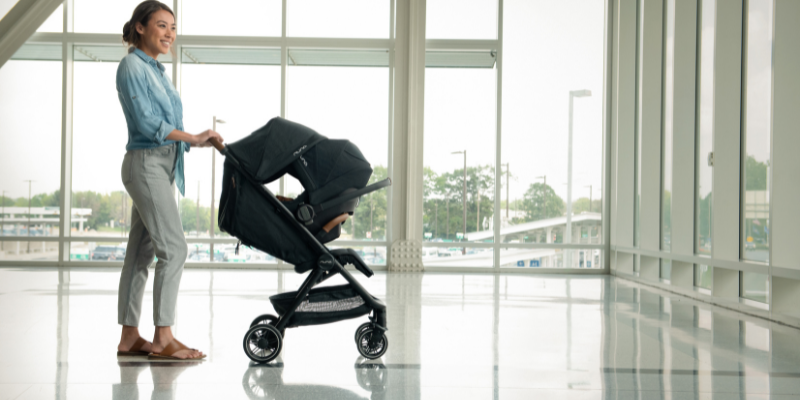 Woman Pushing Nuna TRVL Stroller With Infant Car Seat Attachment