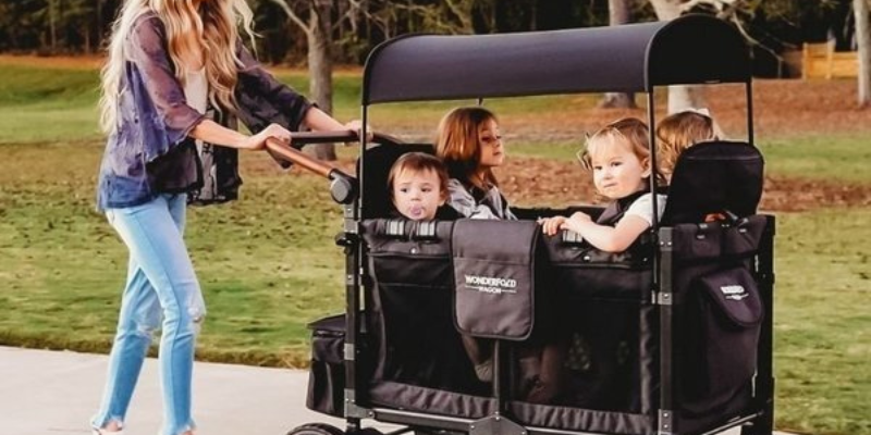 Wonderfold Wagon With Four Children Sitting Inside and Woman Pushing