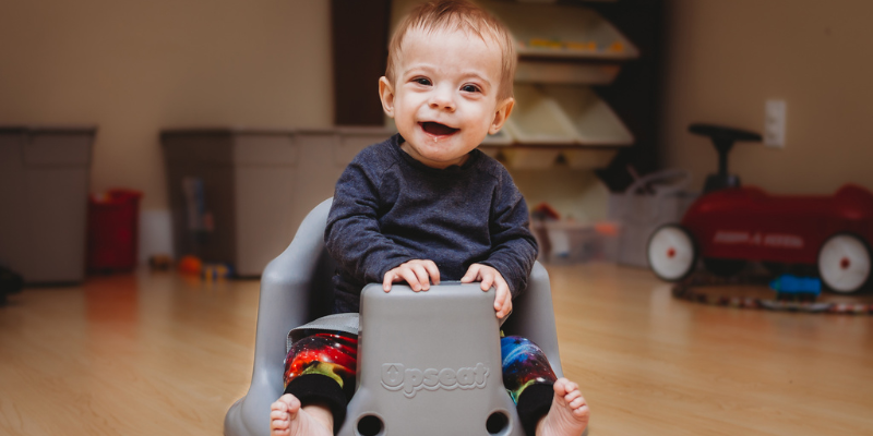 Little Boy Smiling and Sitting in Upseat Booster Floor Seat 