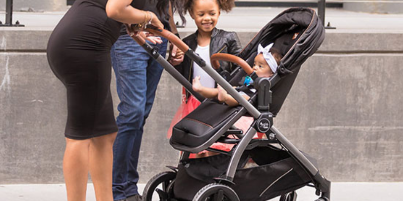 Peg Perego Z4 Agio Stroller With Baby Inside and Little Girl Smiling and Looking In 