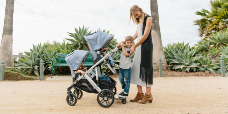 Woman Looking at Little Boy While Holding Vista V2 Stroller With Double Seat Attachment 