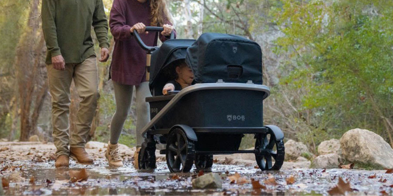 Woman and Man Pushing BOB Renegade Wagon in Forest With Two Children Sitting Inside